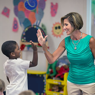 Goddard School childcare franchise owner high-fiving a child